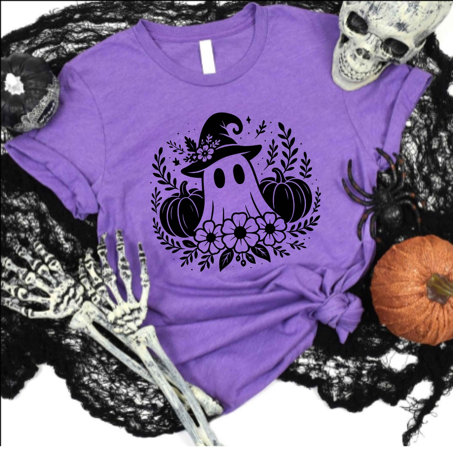 Purple t-shirt with Halloween-themed design featuring a ghost, pumpkins, and flowers on a black lace background.