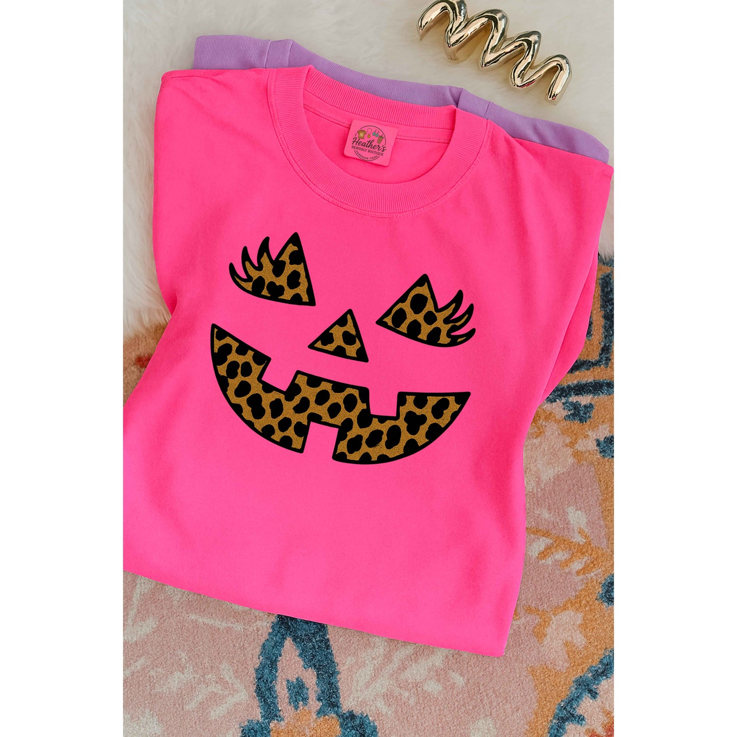 Pink t-shirt with leopard print pumpkin design on a textured surface