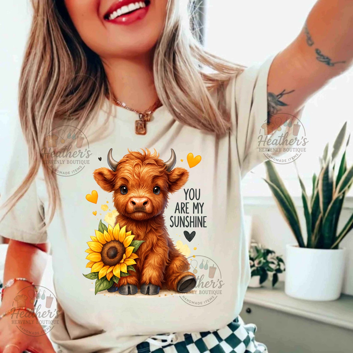 Person wearing a t-shirt with a cow and sunflower design and text 'You are my sunshine'.