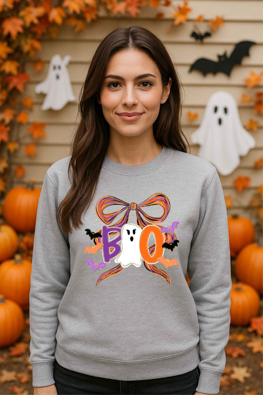 Woman wearing a Halloween-themed gray sweatshirt with pumpkins and ghosts in the background