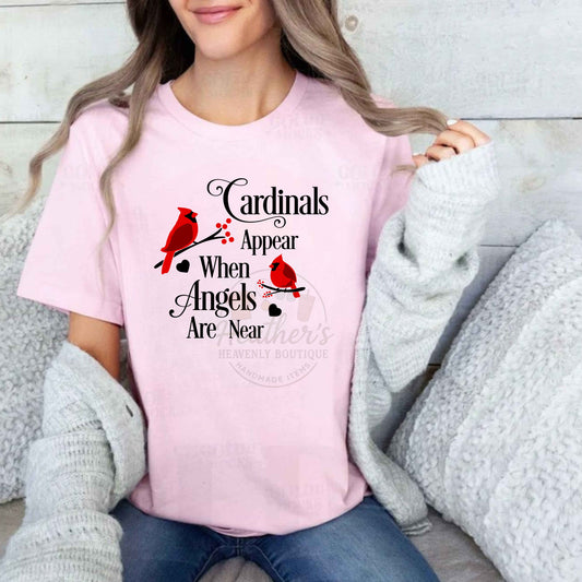 Person wearing a pink t-shirt with cardinals appear when angels are near design and text.