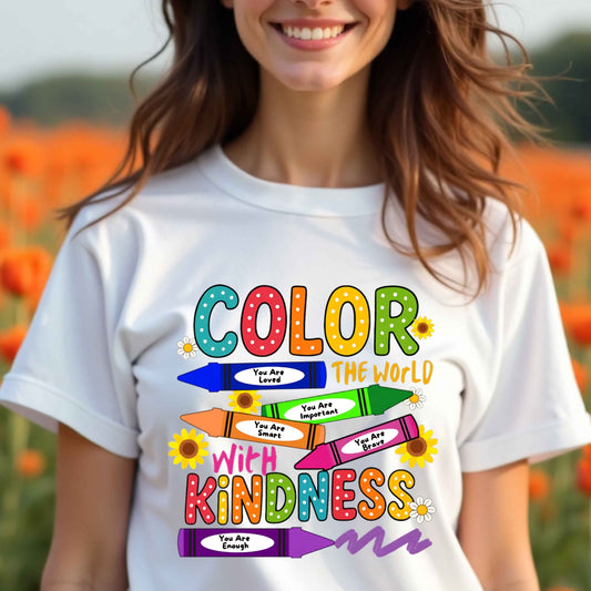 Person wearing a white t-shirt with colorful text and crayon graphics in a field of flowers.