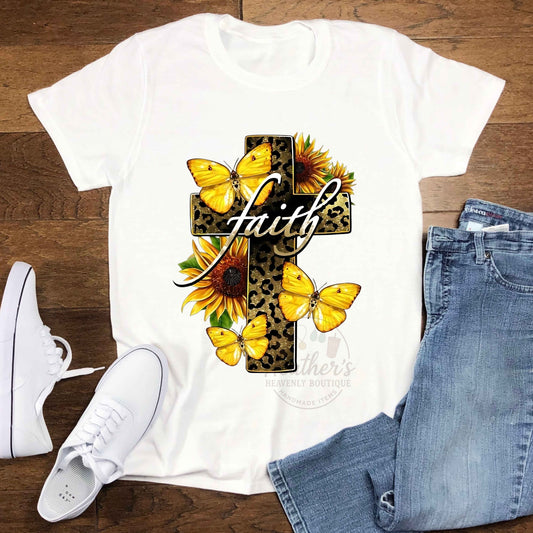 A white T-Shirt with a leopard print cross that says faith with yellow butterfly's and sunflowers. 