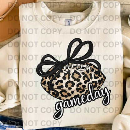 White sweatshirt with leopard print headband and 'gameday' text on a wooden surface.