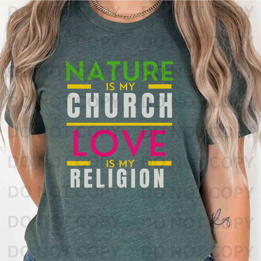 Person wearing a green t-shirt with colorful text design that says, "Nature is my Church Love is my Religion"