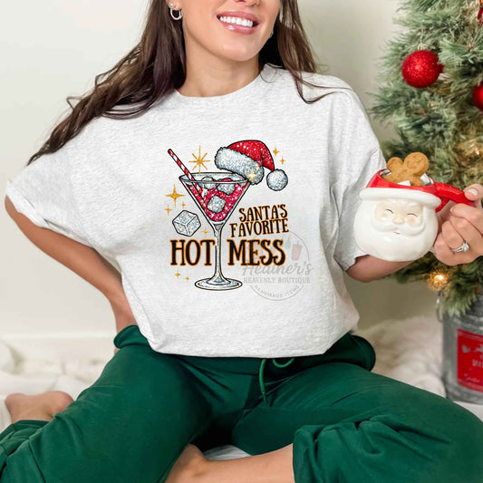 Woman wearing a white t-shirt with a Christmas-themed design, sitting in front of a decorated tree.