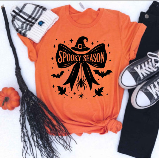 Orange t-shirt with 'Spooky Season' design, broom, pumpkin, and sneakers on a white background