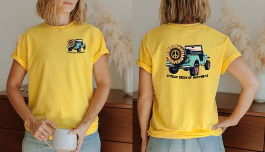 Person wearing a yellow t-shirt with a graphic design on the front and back, holding a mug.